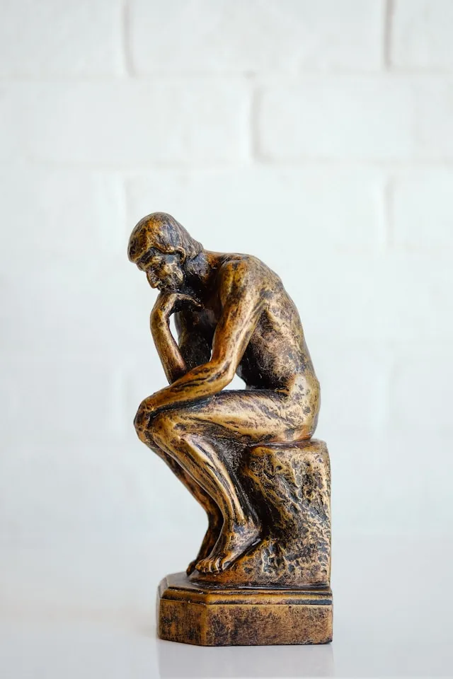 A bronze thinker statuette on a desk